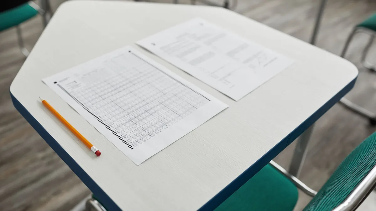 A close-up image of an exam paper and pencil on a classroom desk, ready for a test.