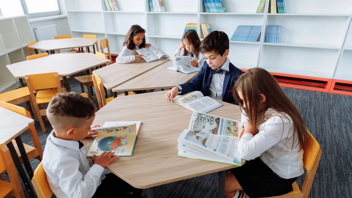 Group of school children engaged in reading at a modern library table.