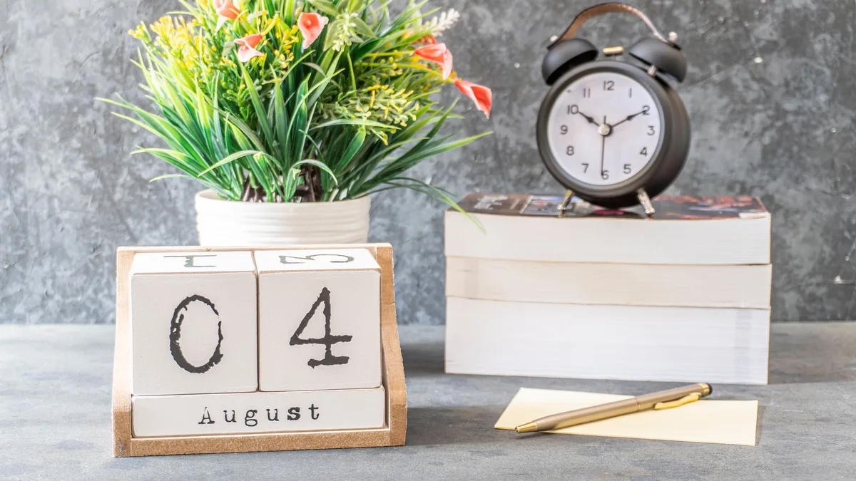 A styled indoor setup featuring a calendar showing August 4 and an alarm clock on books.